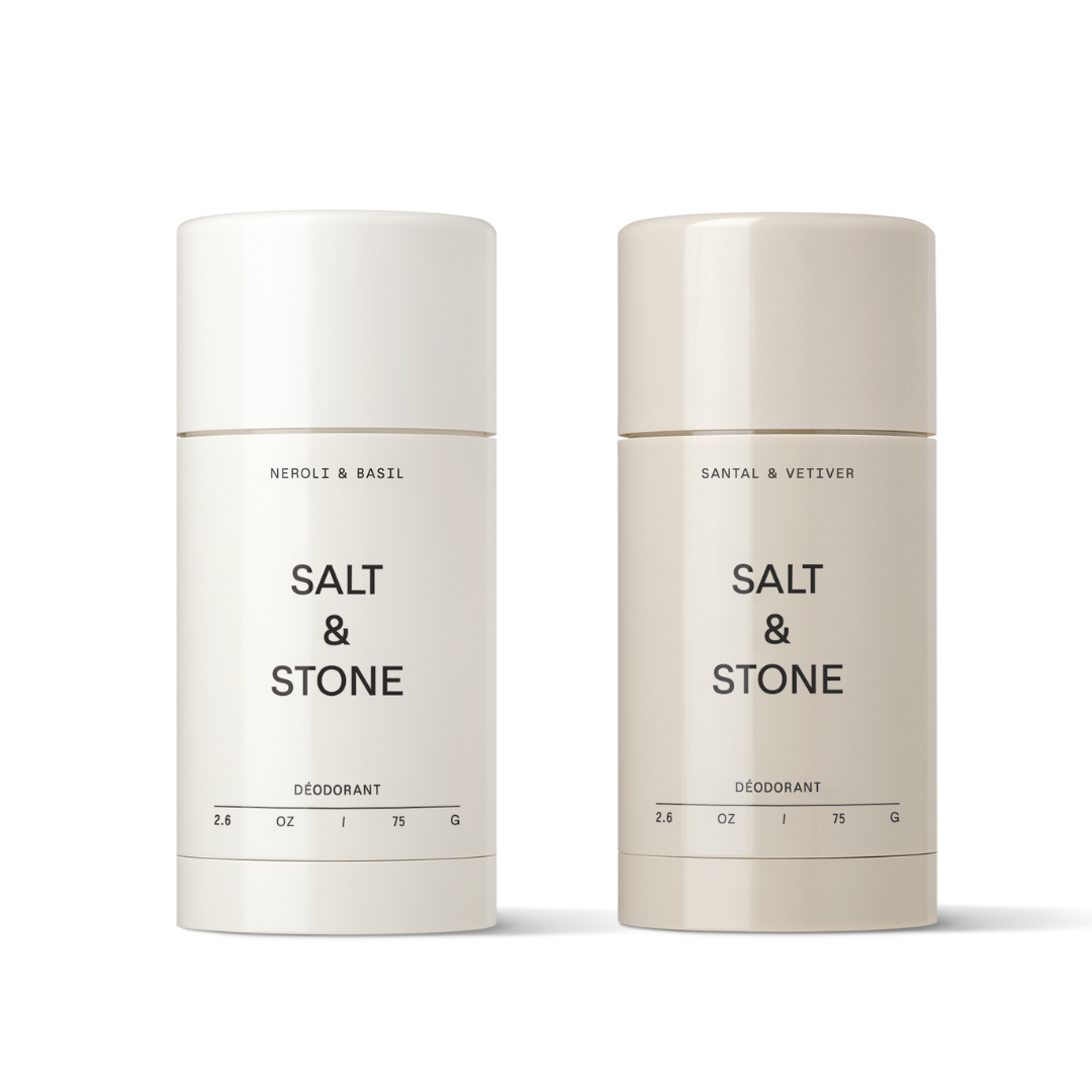 Two cylindrical deodorant sticks with white labels, one labeled 'Neroli & Basil' and the other 'Santal & Vetiver', both from the brand Salt & Stone.