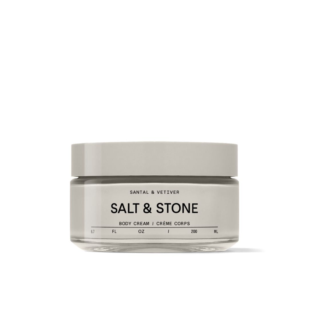 A jar of Santal & Vetiver Salt & Stone body cream, featuring a minimalist light gray lid and matching label on a clear glass jar, set against a plain white background.